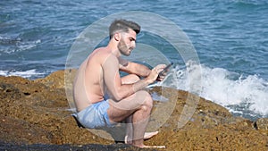 Young man at sea reading with ebook reader