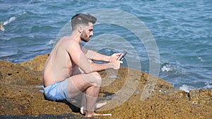 Young man at sea reading with ebook reader