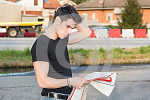Young man searching for a location from printed