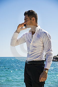 Young man at the seaside talking on cell phone