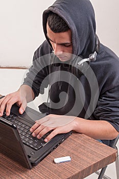 Young man seated on his desk working with laptop and listen mu