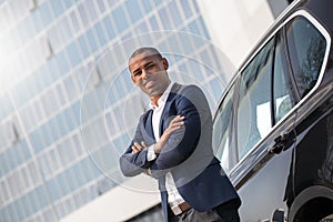 Young man security standing near car crossed arms looking camera cheerful side view