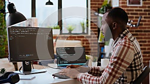 Young man seen programming software code on his laptop in a sleek home office