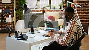Young man seen programming software code on his laptop in a sleek home office