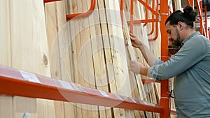 Young man selecting wood boards in a hardware store or warehouse