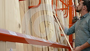 Young man selecting wood boards in a hardware store or warehouse
