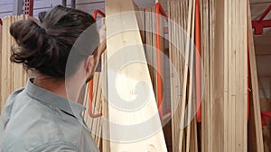 Young man selecting wood boards in a hardware store or warehouse