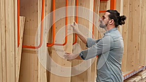 Young man selecting wood boards in a hardware store or warehouse