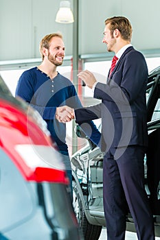 Young man and seller with auto in car dealership