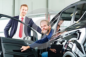 Young man and seller with auto in car dealership