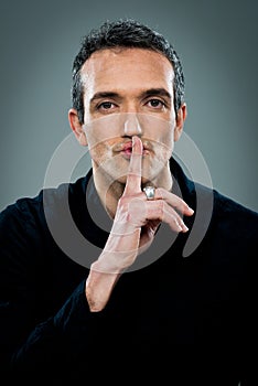 Young Man with Serious Expression Doing a Silent Sign photo