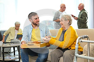 Young man serving dinner for elderly woman in hospice. Senior people care