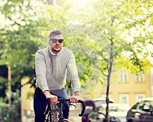 Young man in shades riding bicycle on city street