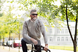 Young man in shades riding bicycle on city street