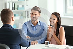 Young man shaking hands with estate agent in office