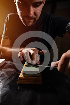 Young man sharpening the knife
