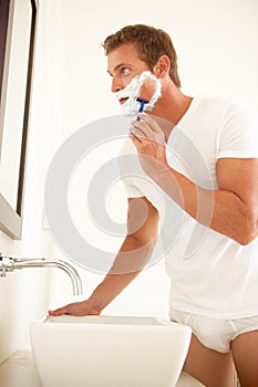 Young Man Shaving In Bathroom Mirror