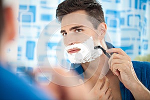 Young man shaving using a razor