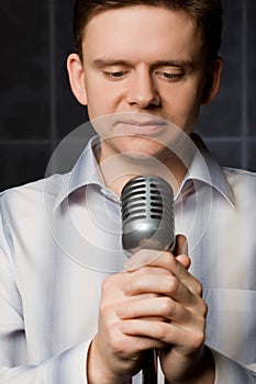 Young man in shirt keeps in hands microphone