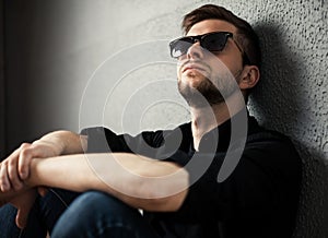 Young man in shirt siting with hands clasped