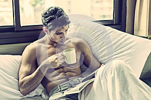 Young man shirtless on his bed with a coffee or tea cup photo