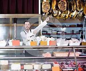 Young man shop assistant demonstrating sorts of meat in shop