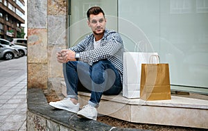 Young man with shopping bags sitting