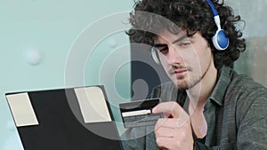 Young man shopping online with credit card using smart phone at home.