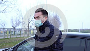 Young man with short haircut in blue mask gets out of car