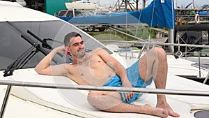 A young man in shorts lies and tans on a boat.