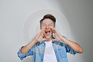 Young man shouting with hands cupped to his mouth.