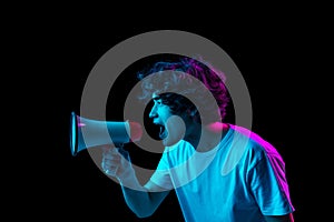 Young man shouts through a megaphone isolated over dark background in neon