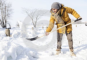 Young man shoveling snow in the country