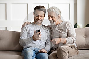 Young man showing funny video on smartphone to happy father.