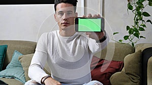 Young man showing his cell phone`s blank green screen