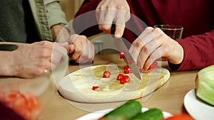 A young man is showing his friend how to cut chilly pepper properly