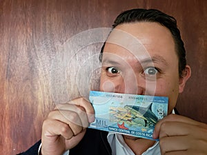 young man showing and holding a Costa Rican banknote of 2000 colones