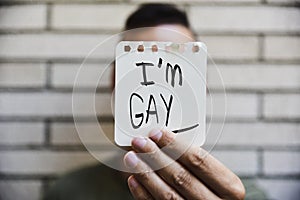 Young man showing a note with the text I am gay