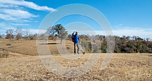 Young man showing thumps up after reaching hill/mountain`s peak successfully