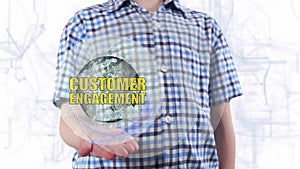 Young man shows a hologram of the planet Earth and text Customer engagement