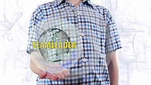 Young man shows a hologram of the planet Earth and text Teamleader