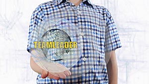 Young man shows a hologram of the planet Earth and text Teamleader photo
