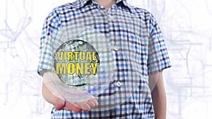 Young man shows a hologram of the planet Earth and text Virtual money