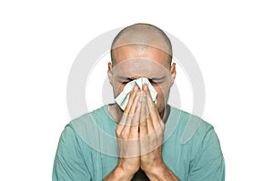 Young man sick from common cold flu blowing his nose with paper tissue isolated on white background.