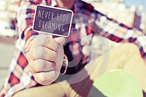 Young man with a signboard with the text never stop dreaming