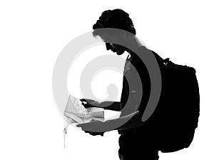 Young man silhouette backpacker reading map