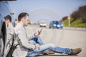 Young man with a silver car that broke down on the road