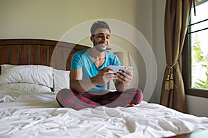 Young Man Sit On Bed, Happy Smile Hispanic Guy Bedroom Using Cell Smart Phone