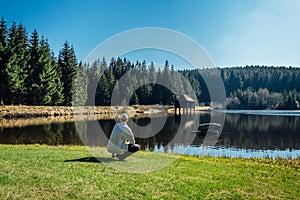 Young man sit on nice clean pond with wooden building and spring tree with blue sky