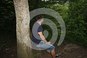 A young man sits in the forest on the nature